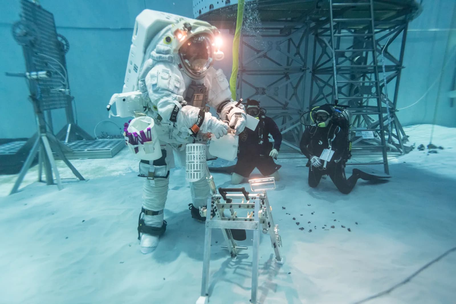 Artemis spacesuit testing underwater with divers nearby.