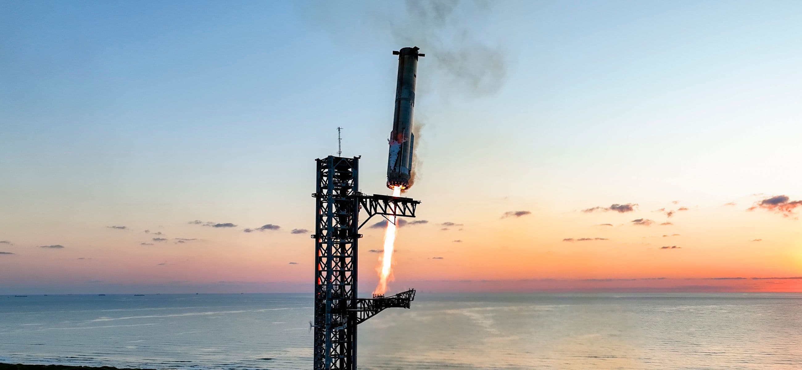 A Starship and Super Heavy flight test climbing through launch exhaust at Starbase.